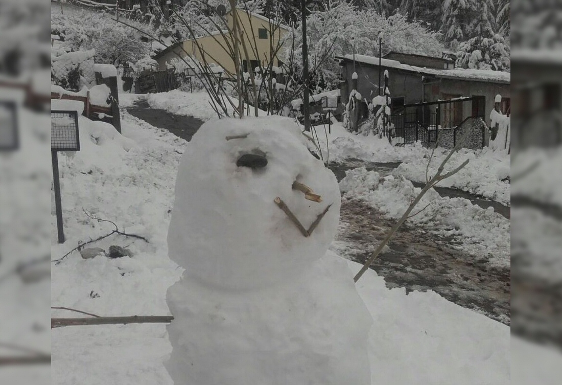 Un muñeco de nieve posa feliz en esta postal de Esquel (Gustfront).
